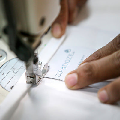 Close Up Of Dip & Doze Label Being Sewn On To Bedding | Dip & Doze